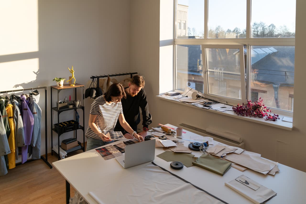 Two people in a design studio reviewing fabric samples together at a work table